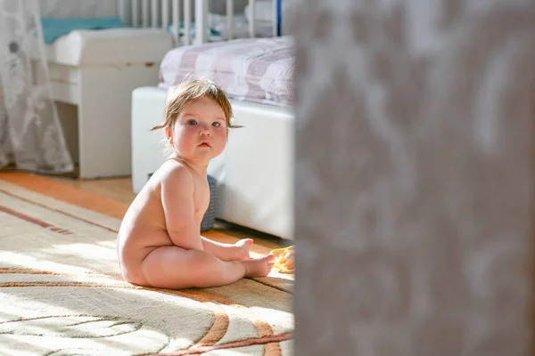 Kind sitzt im Schlafzimmer. Baby, das auf dem Bett kriecht. kleines Kind spielt im weißen, sonnigen Schlafzimmer. Kleinkind lernt zu kriechen. Kinderkrippe. Textilien, Kleidung und Bettwäsche für Kinder. Hungersnöte — Stockfoto