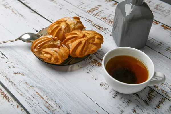 Kopje koffie en romig deeg. Kopje koffie en gebak samenstelling. Kopje koffie en zoete gebak met room vulling op een lichte achtergrond — Stockfoto