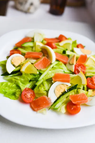 Zeleninový salát na bílém talíři. Čerstvý salát s vejcem, rajčaty, špenátem a avokádem na bílém dřevěném podkladu. Zdravé jídlo. — Stock fotografie