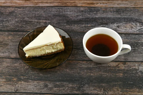 Käsekuchen mit Kaffee auf dunklem Holzgrund. Blick von oben. Daneben ein Käsekuchen auf braunem Holzgrund. Retro-Tasse. Kaffee im Café, Kopierraum. — Stockfoto