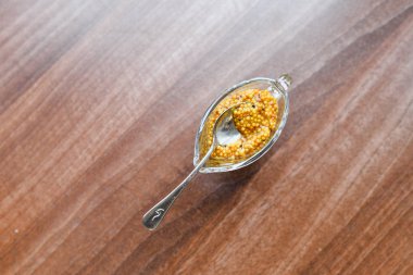 Cam kasede hardal. Bir kasede Fransız tahıllı hardal. Beyaz ahşap masada cam bir kasede Fransız tahıllı hardal.