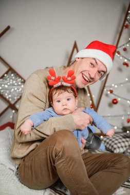 Babası oğluyla birlikte sarılıp eğleniyor. Aşk, mutluluk ve büyük bir aile kavramı. Baba ve oğul yeni yılda eğlenirler. Yeni Yıl dekoru.