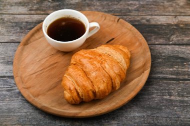 Kruvasanla kahvaltı. Sabahın başlangıcında. Taze Fransız kruvasanı. Kahve fincanı ve ahşap arka planda taze pişmiş kruvasan. Yukarıdan bak. Sabah kahvaltısı kruvasan ve kahveyle