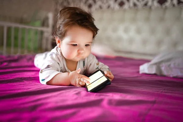 Kind leert via mobiele telefoon. Kleine pasgeboren baby bereiken voor een mobiele telefoon — Stockfoto