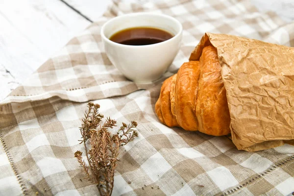 Café con croissant. el comienzo de la mañana. Una taza de café. croissant francés fresco. Cafetería y croissants recién horneados en un entorno de madera. Vista desde arriba.. — Foto de Stock