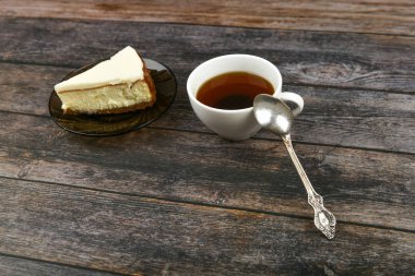 Koyu ahşap arka planda kahveli cheesecake. Yukarıdan bak. Kahverengi ahşap arka planda yanında bir cheesecake. Retro bardak. Kahve dükkanında kahve, fotokopi odası..