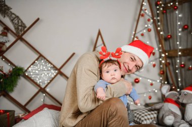 Babası oğluyla birlikte sarılıp eğleniyor. Aşk, mutluluk ve büyük bir aile kavramı. Baba ve oğul yeni yılda eğlenirler. Yeni Yıl dekoru.