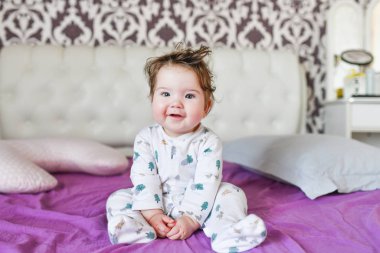 Aydınlık bir yatak odasında yeni yürümeye başlayan bir çocuk. Tatlı bir rüyadan sonra. çok renkli çarşaflar