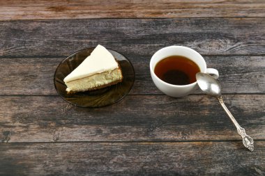 Koyu ahşap arka planda kahveli cheesecake. Yukarıdan bak. Kahverengi ahşap arka planda yanında bir cheesecake. Retro bardak. Kahve dükkanında kahve, fotokopi odası..