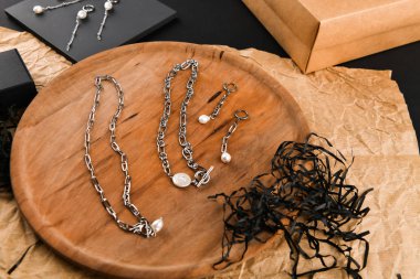 Zincirli gümüş küpeler. Yakın plan. Tahta bir tezgahta yatıyordu. Yukarıdan bak. Mücevher ve mücevher kavramı. Kadınlar için hediyeler. Alışveriş. El işi.