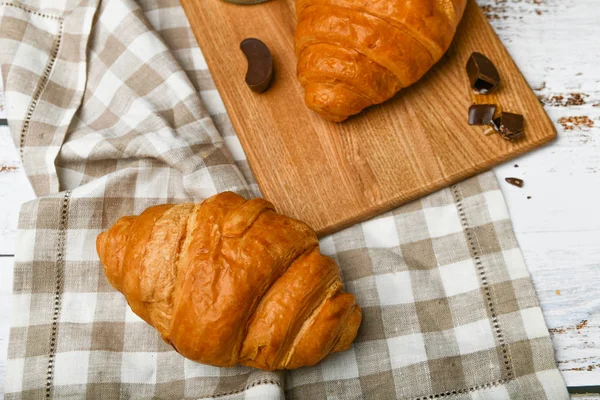 Čokoládové croissanty. na začátku dopoledne. Šálek kávy. Čerstvý francouzský croissant. Šálek kávy a čerstvé pečené croissanty na dřevěném pozadí. Pohled shora. — Stock fotografie