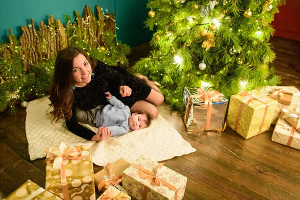 Barnet med mamma vid jul. Glad familj mamma och lille son leker hemma på julhelgen. Nyårshelgen. Leksak med mamma i det festligt inredda rummet med julgran. Po — Stockfoto