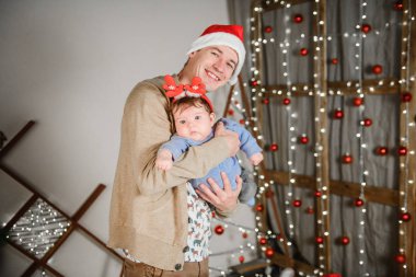 Babası oğluyla birlikte sarılıp eğleniyor. Aşk, mutluluk ve büyük bir aile kavramı. Baba ve oğul yeni yılda eğlenirler. Yeni Yıl dekoru.