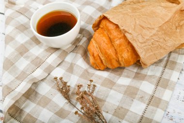 Sabah ayçöreğiyle. Sabahın başlangıcında. Taze Fransız kruvasanı. Kahve fincanı ve ahşap arka planda taze pişmiş kruvasan. Yukarıdan bak. Sabah kahvaltısı kruvasan ve kahveyle