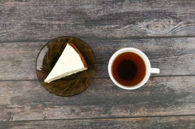 Koyu ahşap arka planda kahveli cheesecake. Yukarıdan bak. Kahverengi ahşap arka planda yanında bir cheesecake. Retro bardak. Kahve dükkanında kahve, fotokopi odası..