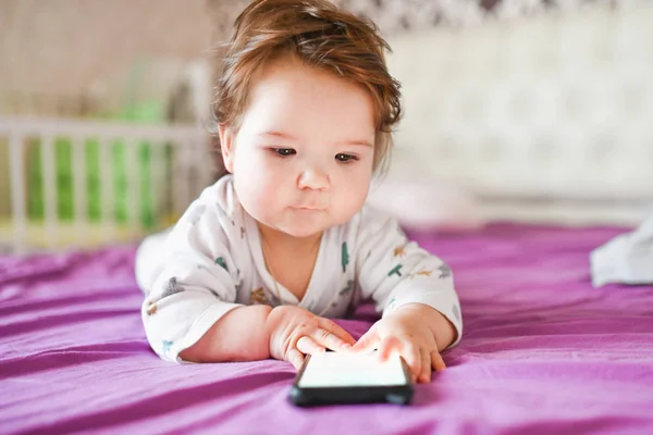Ребенок учится по мобильному телефону. Маленький новорожденный ребенок тянется к мобильному телефону — стоковое фото