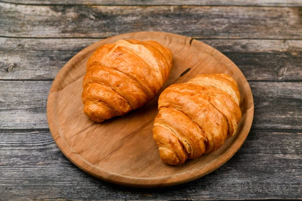 Dos croissants. Croissant francés fresco. sobre un fondo de madera. Vista desde arriba. Desayuno por la mañana con croissant. Desayuno francés. Gran hogar. Torre fresca. — Foto de Stock