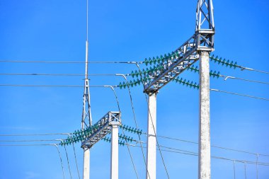 Yüksek voltajlı elektrik direkleri beyaz bulutlu mavi gökyüzüne karşı. elektrik direkleri