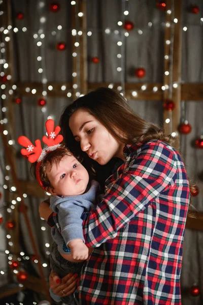 Noel ağacında anne ve bebek kucaklaması. Mutlu bebek ve annesi çerçeveye bakıyorlar. Noel'de oğluyla birlikte anne kucaklıyor. ve eğlenin. yeni yıl için yenidoğan bebek. — Stok fotoğraf