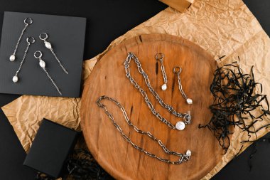 Zincirli gümüş küpeler. Yakın plan. Tahta bir tezgahta yatıyordu. Yukarıdan bak. Mücevher ve mücevher kavramı. Kadınlar için hediyeler. Alışveriş. El işi.