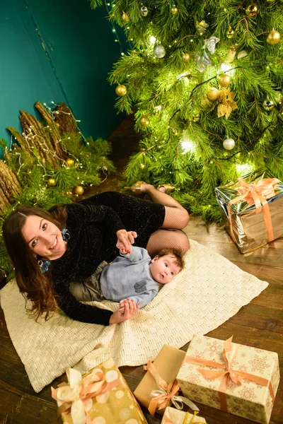 Baby with mother at Christmas. happy family mother and baby little son playing home on Christmas holidays. New Year's holidays. Toddler with mom in the festively decorated room with Christmas tree. Po — Stock Photo, Image