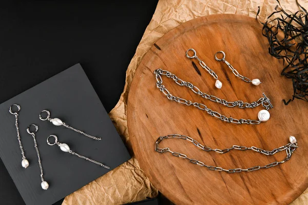 Zincirli gümüş küpeler. Yakın plan. Tahta bir tezgahta yatıyordu. Yukarıdan bak. Mücevher ve mücevher kavramı. Kadınlar için hediyeler. Alışveriş. El işi.