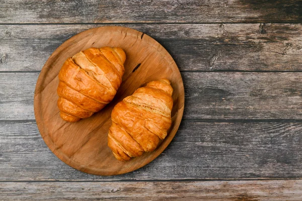 Dos croissants. Croissant francés fresco. sobre un fondo de madera. Vista desde arriba. Desayuno por la mañana con croissant. Desayuno francés. Gran hogar. Torre fresca. — Foto de Stock