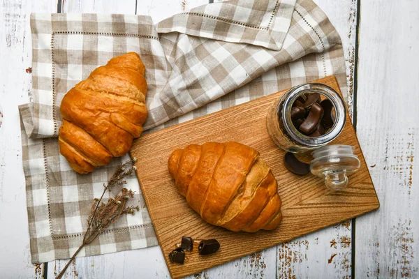 Croissants de chocolate. el comienzo de la mañana. Una taza de café. Croissant francés fresco. Cafetería y croissants recién horneados en un entorno de madera. Vista desde arriba.. — Foto de Stock