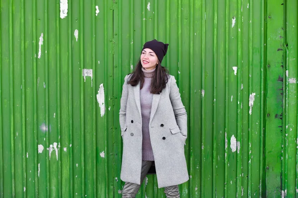 Девушка на зеленом фоне. В теплом сером пальто. Портрет красивой девушки на зеленом фоне — стоковое фото
