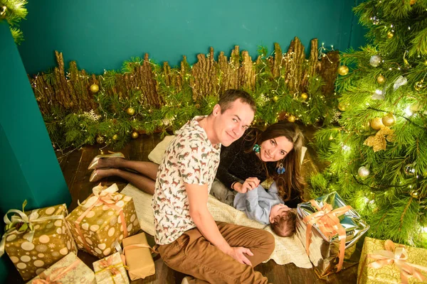 Porträt einer jungen Familie am Weihnachtsbaum. glücklich lächelnde junge Familie neben dem Weihnachtsbaum. Neujahr feiern. Mama und Papa am Weihnachtsbaum. Mutter Vater und Kind an Heiligabend. — Stockfoto