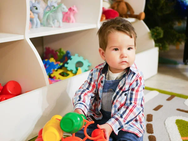A gyerek a játszószobában játszik. Boldog kisfiú játszik a kilátás a színes műanyag játszótér. Imádnivaló gyermek, aki jól érzi magát otthon. — Stock Fotó