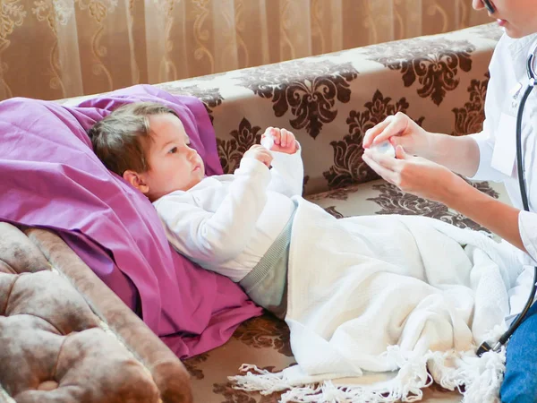 Le médecin de l'enfant donne des pilules à l'enfant. Première rencontre avec un médecin. le médecin est à la maison. appelez l'adresse. Médecin de garde. — Photo