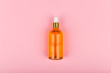 Pembe arka planda etkili bir yağ bidonu. Eko-bakım konsepti. Cilt bakım ürünleri. El işi kağıdı. Daire yalan söylüyordu. Bir damlacıkta altın yağ. Saf kenevir yağı. Üzerinde altın rengi bir damlacık var.