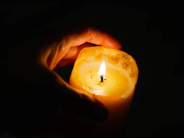 Svíčka v rukou na tmavém pozadí. během festivalu světla — Stock fotografie