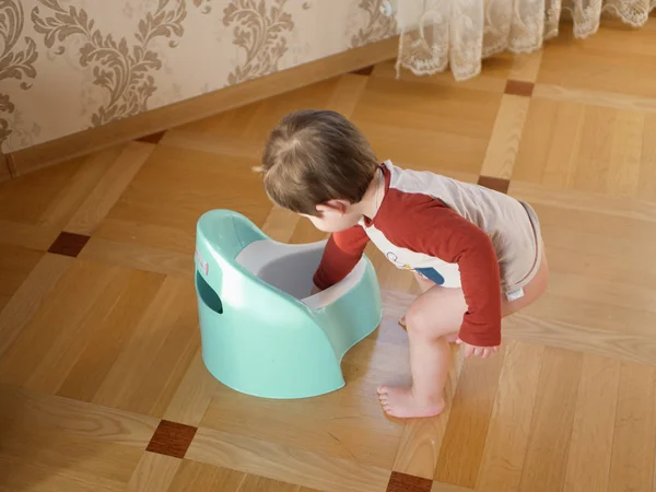 男孩和便盆。可爱的女婴在客厅里玩睡壶。可爱的女婴在客厅的地板上玩睡壶。为学校学习洗手间 — 图库照片
