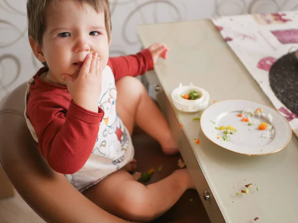 餐桌旁的孩子吃蔬菜.童年、食物和人的概念-幼儿吃饭时吃健康的早餐 — 图库照片
