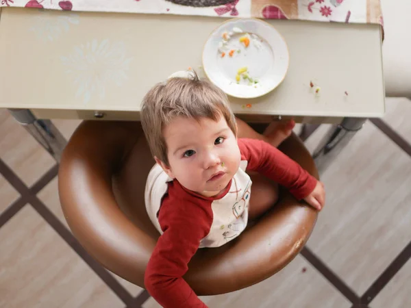 The child at the table eats a top view. childhood, food and people concept - little child eating a healthy breakfast for dinner in a restaurant or cafe