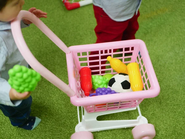 Baby and shopping concept. Un niño compra juguetes para sí mismo. Niño y carro. — Foto de Stock