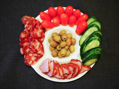 Sebze ve et bir tabakta. Misafirler için atıştırmalık bir şeyler. Koyu arkaplana karşı beyaz plaka