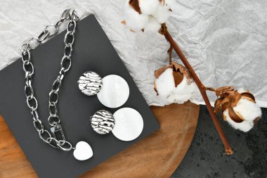 Küpeli gümüş mücevherler. Gümüş zincirli kalp şeklinde bir kolye. Sevgililer Günü için dekorasyon. Ahşap arka planda zincirler. Yukarıdan görüntüle.