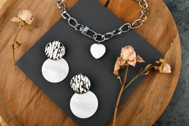 Küpeli gümüş mücevherler. Gümüş zincirli kalp şeklinde bir kolye. Sevgililer Günü için dekorasyon. Ahşap arka planda zincirler. Yukarıdan görüntüle.