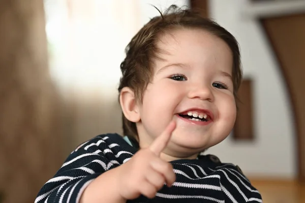 A criança ri e mostra um dedo. A criança tem 0-1 anos. uma criança pequena mostra um dedo com uma mão. retrato de criança de um ano . — Fotografia de Stock