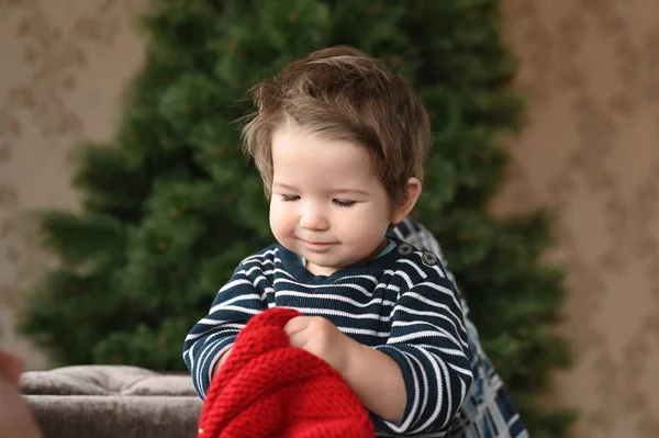 Egy gyerek felvesz egy kalapot. Egy piros kalap és egy gyerek. mutatja az ujját. A gyermek 0-1 éves. egy éves gyermekportré. — Stock Fotó