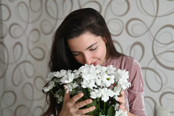 Menina cheira um buquê de flores brancas. Abraços morena cheira um buquê de flores delicadas de sua amada. Um bom presente para sua metade amada . — Fotografia de Stock
