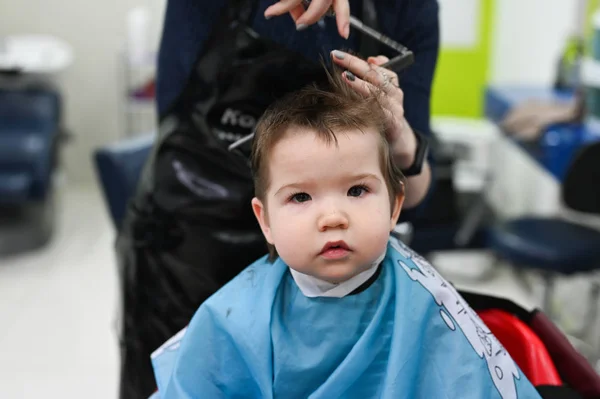Child at the hairdresser close-up. The first haircut of the child at the hairdresser. Baby haircut toddler. — Stock Photo, Image