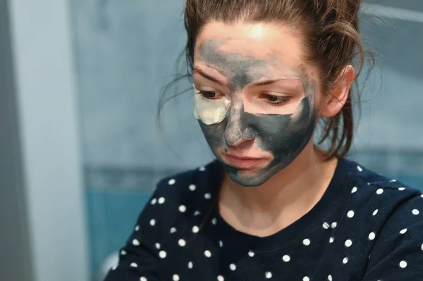 Sensação desagradável da máscara para o rosto. Uma jovem mulher tem um efeito colateral desagradável de testar uma nova máscara facial cosmetologia. Uma mulher está assustada ou desagradavelmente surpreendida por uma sensação de — Fotografia de Stock