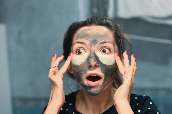 Awesome facial mask feel. The young woman has the Authentic effects of testing a new cosmetology face mask. The woman is pleasantly surprised by the feeling. — Stock Photo, Image