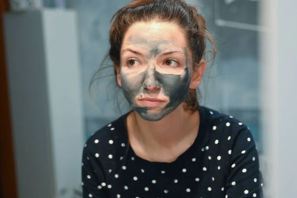 Sensação desagradável da máscara para o rosto. Uma jovem mulher tem um efeito colateral desagradável de testar uma nova máscara facial cosmetologia. Uma mulher está assustada ou desagradavelmente surpreendida por uma sensação de — Fotografia de Stock