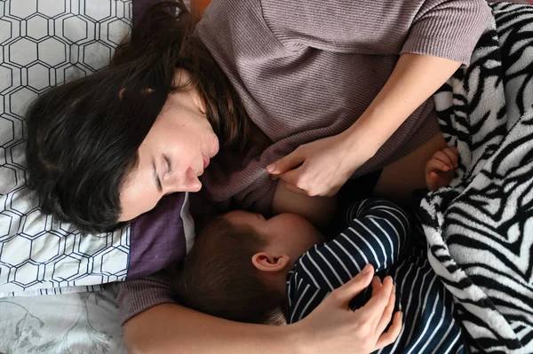 Mamma ger bröst innan läggdags. Ammar ett barn. Mammas och barnets lugna sömn. Ligger på bröstet. — Stockfoto