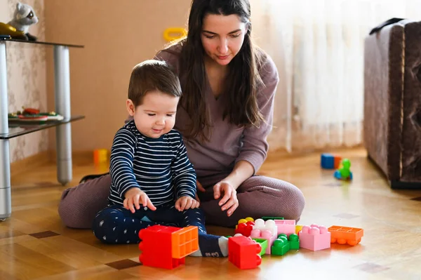 Designerspel mamma och barn. Baby pojke och mor leker tillsammans med konstruktion uppsättning leksak — Stockfoto